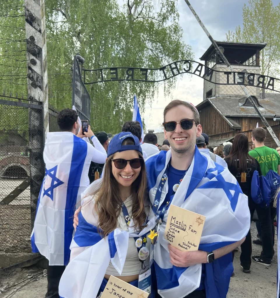Leah and Justin draped in Israeli flags at the Auschwitz gate during the March of the Living.